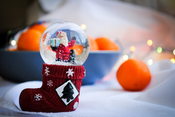 Naklejka premium Snow globe and tangerines on the table. Christmas mood.