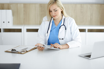 Woman-doctor standing in hospital or clinic and using tablet pc. Data and best service in medicine and healthcare