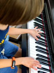 The hands of unknown a caucasian boy who is playing electronic piano.