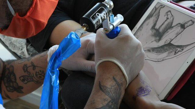 Tattoo artist making its draw on an arm