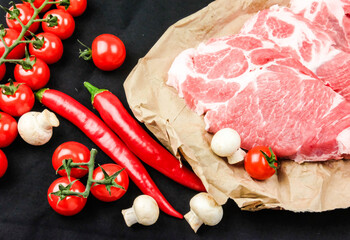 composition of meat tenderloin, cherry tomatoes, chili pepper on a black background. top view. 