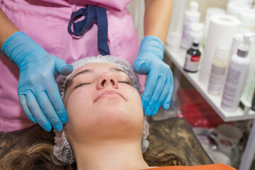 Obraz na płótnie Canvas Beautiful woman enjoying facial massage with closed eyes in spa salon.