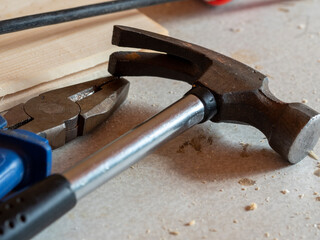 pliers and a hammer are on the table. close-up, hard shadows, selective focus. Tools for the job