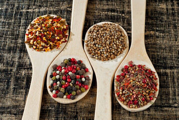 A mixture of various spices in a wooden spoon. Spices and seasonings on an old shabby board. Mix on a pile close up.