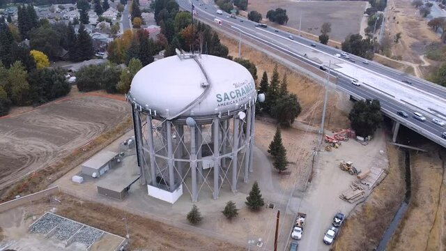 Smooth rotating areal drone shot of the Sacramento Water Tower with a freeway in the  background.