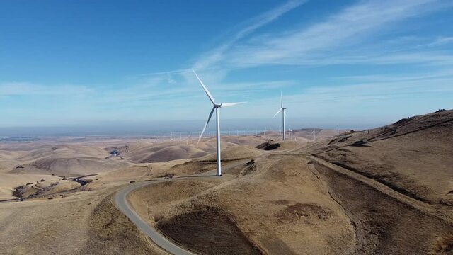 Drone footage of modern windmills in California hills on a bright day