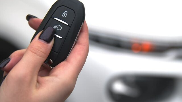 The girl opens the car with an automatic key. 4K, Slow motion, close-up