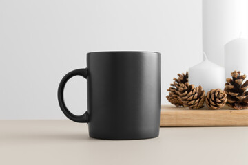 Black mug mockup with candles on a table. Christmas decoration