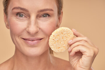 Pretty woman removing makeup with a sponge