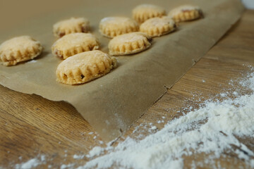 woman prepares butter cookies at home in the kitchen, the table is sprinkled with flour, rolls out the dough, cuts out the shape, the concept of cooking festive food, christmas sweets