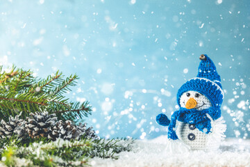 Christmas or winter composition. Little knitted snowmans on soft snow on blue background. Christmas, winter, new year concept.
