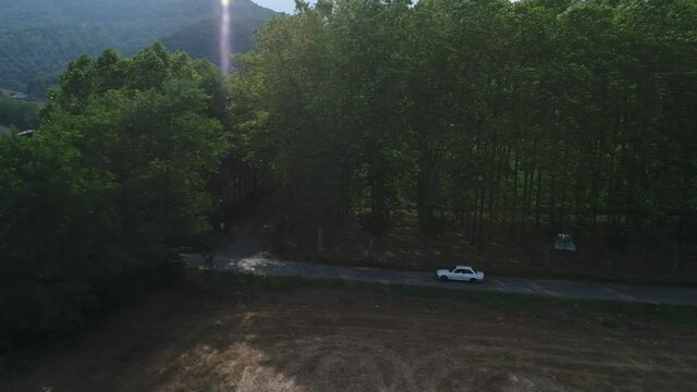 Aerial scene, getting away from an isolated white car driving a rural road
