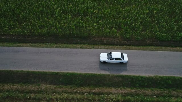Top view aerial tracking, classic E30 BMW moving in a countryside landscape