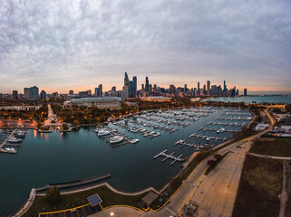 Wide angle Chicago city skyline aerial panorama over the boats and piers in Burnham Harbor with highrise skyscraper buildings along the horizon with a beautiful orange and blue sunset sky above.