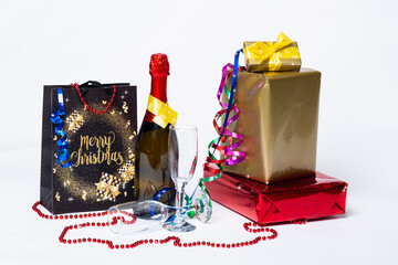 Gift boxes and serpentine, champagne bottle with two glasses on white. Side view with space for your greetings. Christmas greeting card for xmas, New Year 2021. Studio shot, High quality photo.