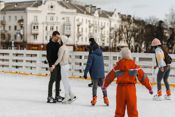 Couple in love skating on the public skating rink. Happy pair having an active date in winter. Winter fun. Winter love story