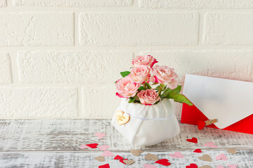 Festive arrangement of bouquet of pink roses and envelope with greeting letter for holidays