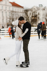 Couple kissing on the public skating rink. Pair skates on the rink. Kissing man and woman. Winter activities. Love story
