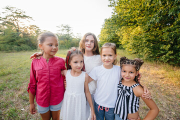 Fototapeta premium A group of cheerful girls are smiling and playing in the Park during sunset. Children's summer camp