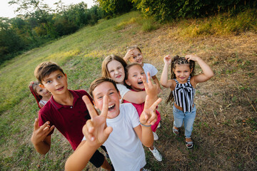 Fototapeta premium A large group of cheerful children sit on the grass in the Park and smile. Games in a children's camp
