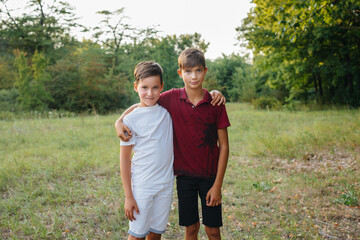 Two small cheerful boys are standing in the Park and smiling. Happy childhood