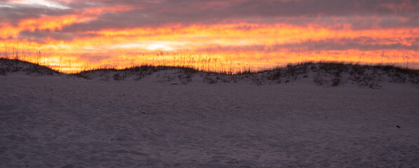 sunset on the beach behind a sand dune