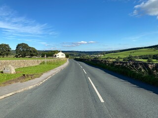 Fototapeta premium Lupton Bank road, as it passes through the village of, Wilsill, on a hot summers day in, Glasshouses, Pateley Bridge, UK