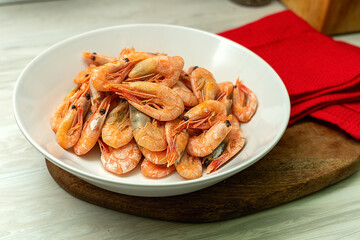 Cooked fresh shrimps on a white plate over old white wooden table with