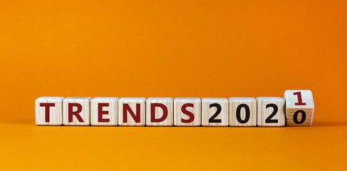 Business concept of new year 2021. Fliped a wooden cube and changes the words 'Trends 2020' to 'Trends 2021'. Beautiful orange background, copy space. New year and trends 2021 concept.
