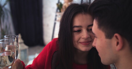 young couple sitting on sofa looking at each other with glasses in hands