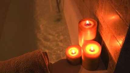 Relaxing home spa bathtub filling up with hot water, for self care, with candles