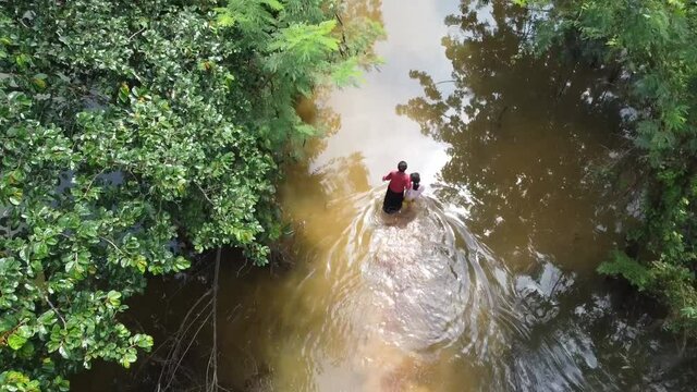 Lonely family Struggling Through A Flooded Street Caused By Heavy Rainfall in Cambodia.Aerial slow motion shot.