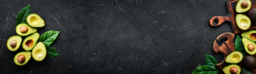 Fresh avocado on a black stone background. Free space for your text. Top view.