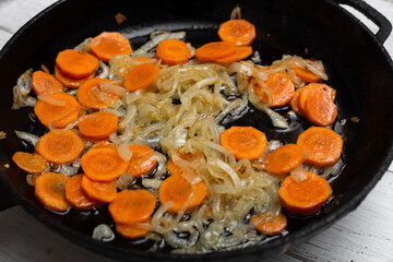 Fried onions and carrots in a pan. Roasting vegetables, cooking ingredients.