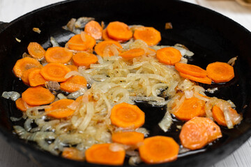 Fried onions and carrots in a pan. Roasting vegetables, cooking ingredients.