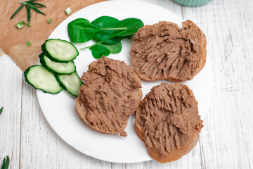 Sandwiches, canapes with chicken pate, tomatoes and cucumbers. On a white wooden background.