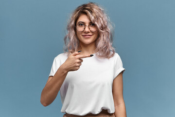 Isolated image of beautiful stylish young woman in trendy glasses and white t-shirt posing against...