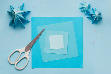 Simple origami 3D Christmas tree made from blue paper. Step by step instruction, step 1. Prepare square sheets of paper different colors and sizes