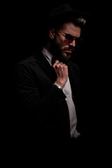Fototapeta premium dramatic cool man in black velvet tuxedo fixing bowtie