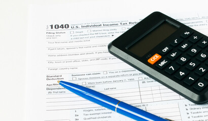 Tax form 1040 with blue pen and calculator
