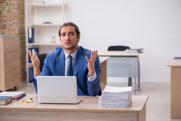 Young male employee and too much work in the office