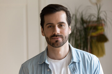 Head shot confident handsome bearded man looking at camera, posing for profile picture, standing at...