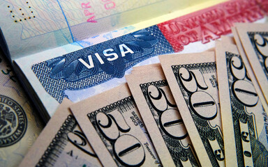 United States visa sticker seen in passport and dollar banknotes placed on top. Concept for travel and immigration cost. VISA application fee.  - obrazy, fototapety, plakaty
