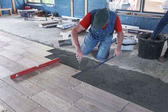 the worker puts ceramic tiles on the construction site