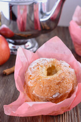 Appetizing muffins with apple and cinnamon in pink paper wrapper close to apple and teapot, vertical orientation