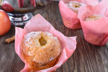 Appetizing muffins with apple and cinnamon in pink paper wrapper close to apple and teapot