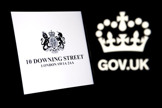 UK Prime Minister's Office logo glowing on the smartphone screen and gov.uk logo on the blurred dark background. Concept.