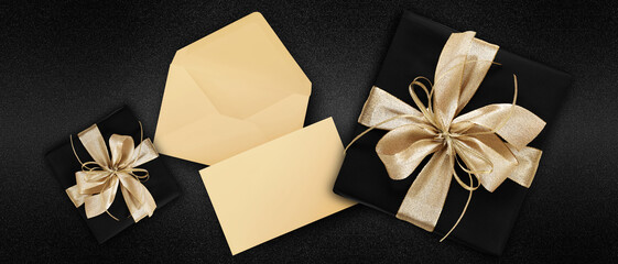 gift card, top view of wrapped present packages with golden ribbon bow, envelope and greeting card , isolated on black background