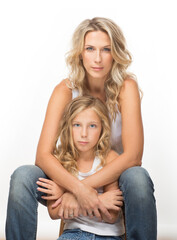 Beautiful blonde mother in singlet, and similar looking curly daughter together in studio, white background.