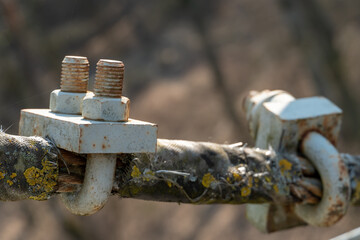 Cables and ropes of the suspension bridge close-up. Repair of the old bridge over the river. Rusty iron cables connected by a bracket and a thick bolt.